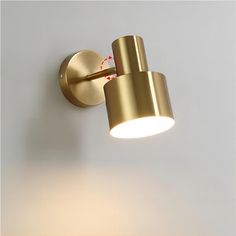 a gold wall light on a white wall with a red line going through it and the lamp is turned off