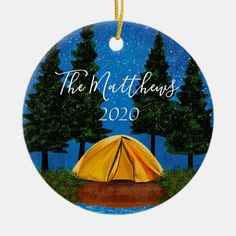 a christmas ornament with a yellow tent in the woods and stars above it