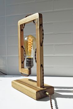 a light bulb in a wooden frame on a white surface with a chain attached to it