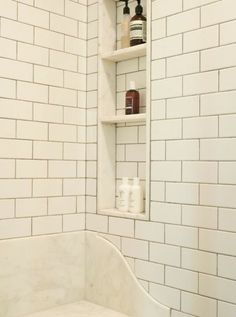 a bathroom with white subway walls and shelves