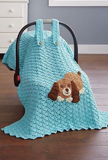 a crocheted teddy bear blanket sitting on top of a chair next to a suitcase