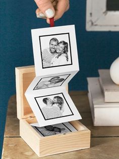 a person is placing pictures on top of a wooden box with two photos inside it