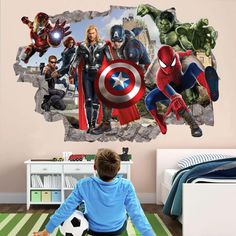 a boy sitting on the floor in front of a wall mural with avengers and spider - man