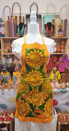 a dress made out of sunflowers on display in a shop with other handbags and purses