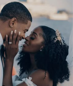 a bride and groom kissing each other in front of a cityscape at sunset