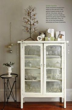 a white china cabinet with glass doors and shelves filled with dishes on top of it