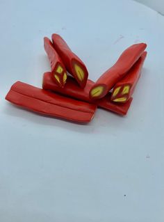 three pieces of red plastic with yellow eyes on them sitting on a white table top