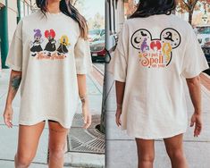 a woman in mickey mouse t - shirt and shorts walking down the street