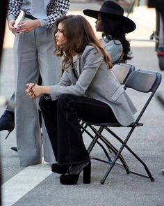 a woman sitting on top of a chair next to a man in a suit and hat