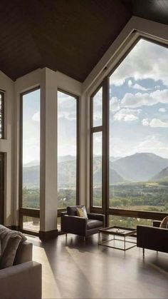 a living room filled with furniture and large windows overlooking the mountains in front of them