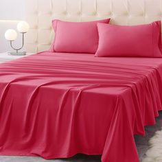 a bed covered in pink sheets and pillows