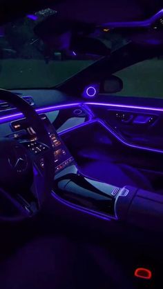 the interior of a car is lit up with purple lights and features steering wheel controls