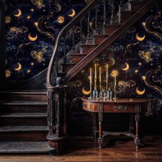 a staircase leading up to a table with candles on it in front of a wallpapered stairway