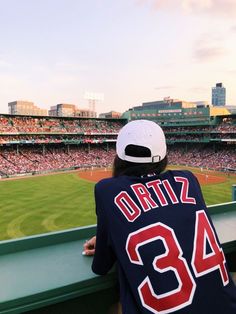 a baseball player sitting in the bleachers at a stadium with his jersey draped over his shoulder