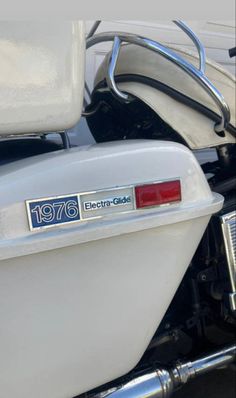 the back end of a white motorcycle with an emblem on it's tailgate