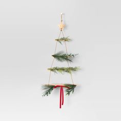 a small christmas tree hanging from the side of a wall next to a red ribbon