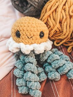 there is a crocheted octopus on the bed next to some yarns and balls