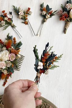 someone is arranging flowers on the table with their hair pins and combs to make them look like they have been pinned together