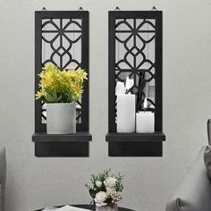 two mirrors on the wall above a table with flowers and candles