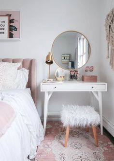 a bedroom with a pink rug, white bedding and a mirror on the wall