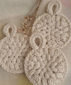 two crocheted coasters sitting on top of a white cloth covered tablecloth