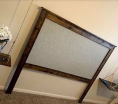 a wooden frame holding a white flower vase on top of a carpeted floor next to a wall