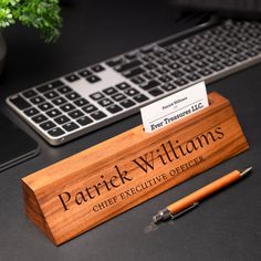 a wooden business card holder sitting on top of a desk next to a computer keyboard