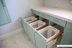 two laundry baskets are in the middle of a kitchen cabinet with drawers on both sides