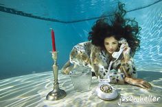 a woman laying on the ground next to a phone and a candle in the water