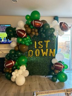 balloons and footballs are on display in front of a backdrop that says, it's down