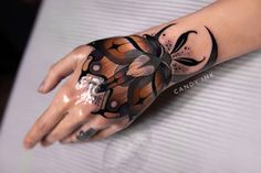 a woman's hand with an orange and black butterfly tattoo on her left arm