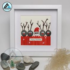 some rocks are sitting next to a framed picture with santa's sleigh on it