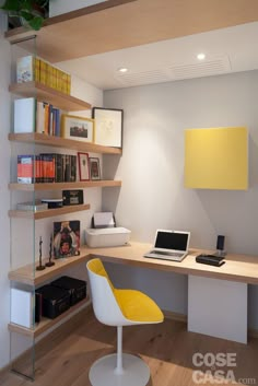 a laptop computer sitting on top of a wooden desk next to a yellow and white chair