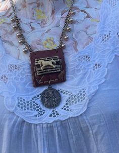 a necklace with a dog on it and a coin hanging from the front, sitting on top of a lace doily