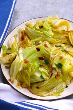 a white plate topped with lettuce on top of a blue and white table cloth