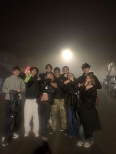 a group of people standing in the middle of a street at night with their arms around each other