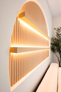 a white couch sitting under a window next to a potted plant and wooden shelf