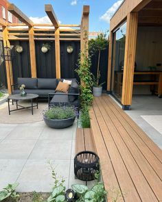 a wooden deck surrounded by plants and potted plants on the other side of it