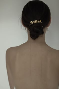 the back of a woman's head with gold hair pins on her left side