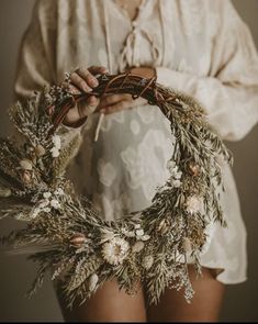 a woman holding a wreath with flowers on it