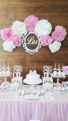 pink and white dessert table with cake, cupcakes and flowers on the wall