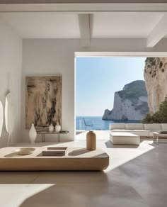 a living room filled with white furniture next to a large open window overlooking the ocean