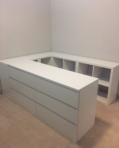 an empty room with two white drawers and a shelf on the wall next to it