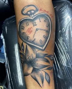 a tattoo with a clock and flowers on it