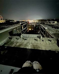 someone's feet on the roof of a building at night