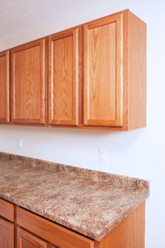 an empty kitchen with wooden cabinets and granite counter tops