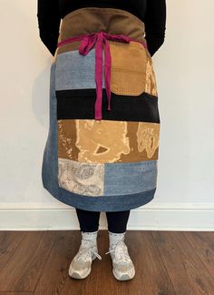 a woman standing in front of a wall wearing an apron made out of old jeans