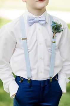 a young boy in a white shirt and blue suspenders is wearing a bow tie