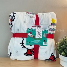 the hello kitty blanket is on display next to a potted plant