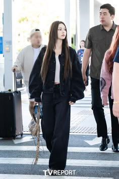 a woman with long hair walking across a cross walk